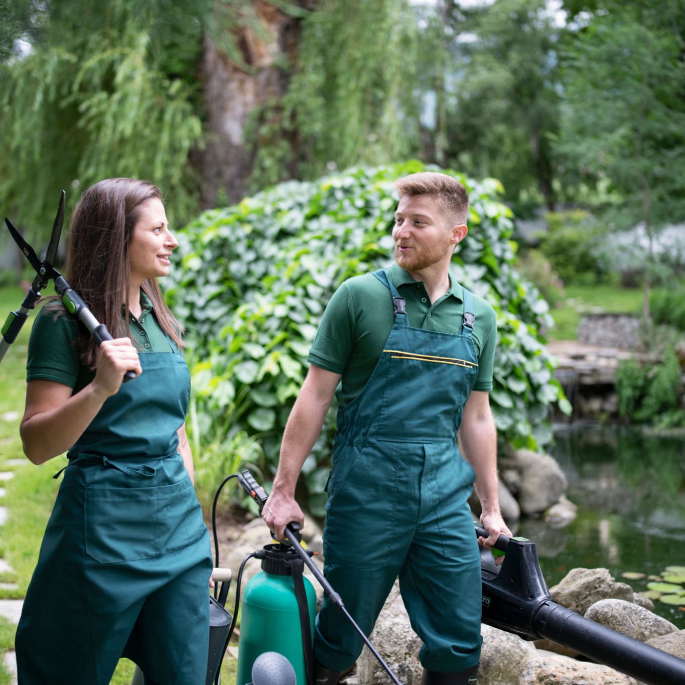 Man and woman are walking in garden and carrying gardening equipment.